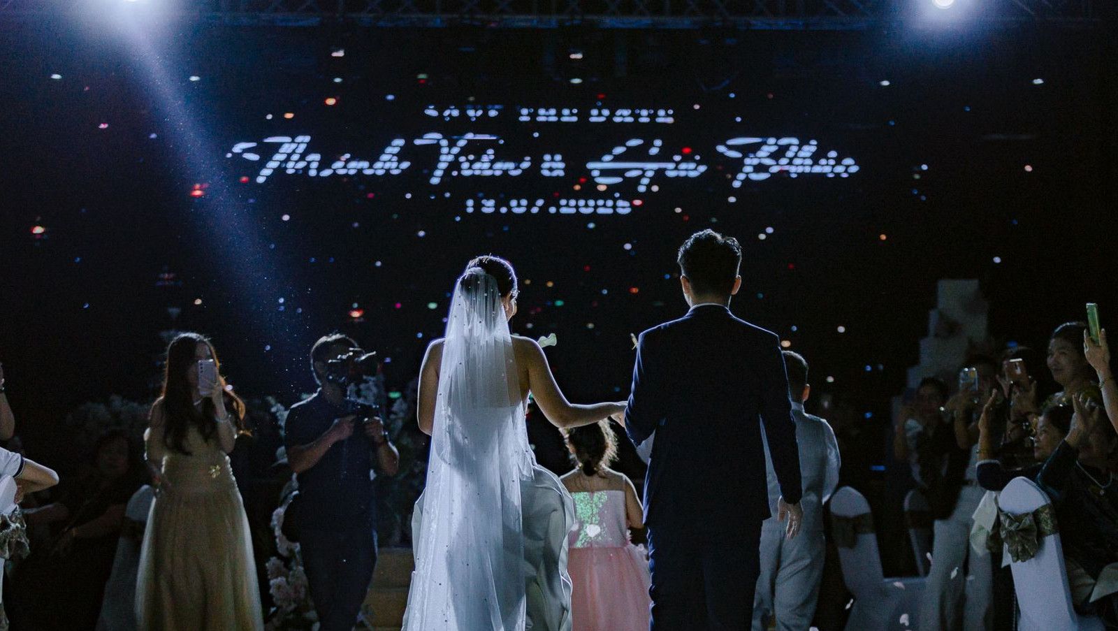 Bride and groom walking down aisle at a beautiful indoor wedding ceremony with guests watching.