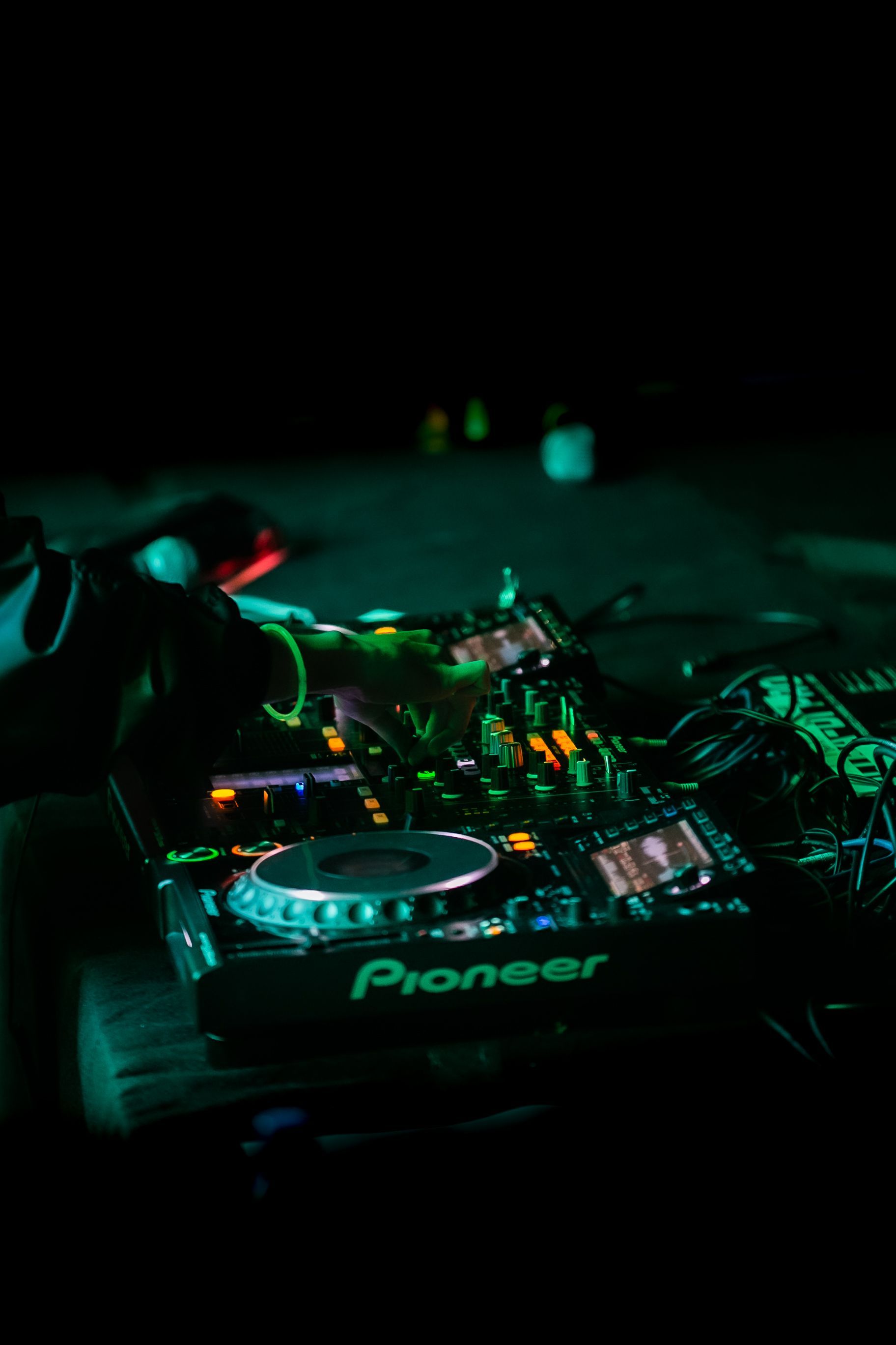 Vibrant DJ mixing electronic music on a Pioneer controller in a lively nightclub setting.